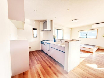 明るい日差しが差し込むキッチンです。カウンター付きで開放感のある空間となっています。床の木目が温かみを感じさせます。収納スペースも充実しています。清潔感のある内装が魅力です。