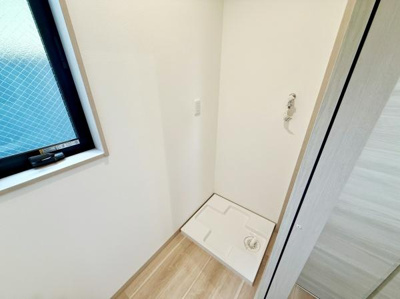 明るい採光のある空間に洗濯機置場が設けられています。床や壁の色合いが清潔感を演出します。コンパクトにまとめられた設計で動線もスムーズです。窓があり換気もしやすい環境です。