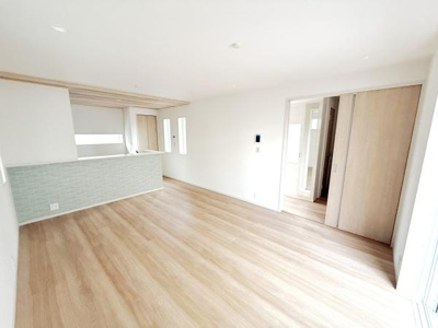 リビングの床は明るい色合いで室内全体が広く感じられます。大きな窓から自然光が入りやすく開放的な雰囲気です。隣接したキッチンとのつながりもスムーズです。スライドドアで空間の使い分けができます。