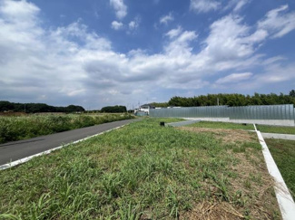 広々とした敷地が広がる現地土地写真です。周囲には自然が多く開放感のある景観が特徴です。整然とした区画が見受けられ様々な用途への活用が期待できます。道路に面しておりアクセスもスムーズです。