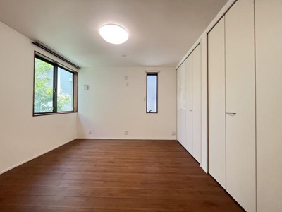 洋室は明るい色合いの壁とブラウンのフローリングが調和しています。大きな窓からは自然光がしっかり差し込みます。クローゼットも複数あり収納力も確保されています。シンプルで使いやすい空間となっています。