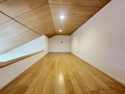 木目調の天井とフローリングが空間全体を明るく演出しています。窓からの自然光がやさしく差し込む設計です。天井のデザインが個性的なアクセントになっています。