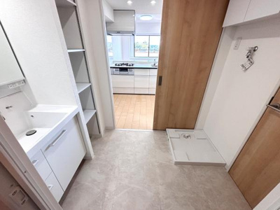 洗面台や収納スペースがすっきりと配置されています。キッチンへの動線も短く使いやすい設計です。洗濯機置き場も確保されており家事が効率的に行えます。清潔感のあるシンプルな内装が特徴です。