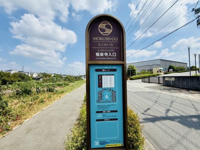 MOKUSEI-GOの福泉寺入口の案内板が設置されています。青空と道沿いの開放感が印象的なロケーションです。周辺には緑も多く散歩道としても利用しやすい環境です。