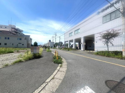 前面道路は幅員が十分にあり車の出入りがしやすいです。道路沿いには建物が整然と並び雰囲気が落ち着いています。舗装もしっかりしており歩きやすい点が特長です。周囲には緑も点在しており見通しが良いです。