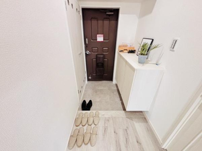 玄関にはシンプルな収納スペースがあり整理がしやすい印象です。明るい内装で清潔感があります。床の色合いが玄関全体の雰囲気を引き立てています。玄関扉はしっかりとした造りです。