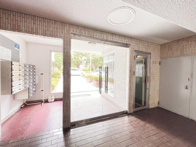 ガラス扉が設置されており開放的な雰囲気のエントランスです。郵便受けも整然と配置されています。タイル張りの床でお手入れもしやすい印象です。外まで見通せるため明るさが感じられます。