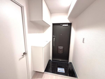 収納スペースが充実した玄関です。白を基調とした内装が明るく清潔感を演出しています。床のタイルが空間にメリハリを与えています。照明がしっかりと設置されており安心して利用できます。