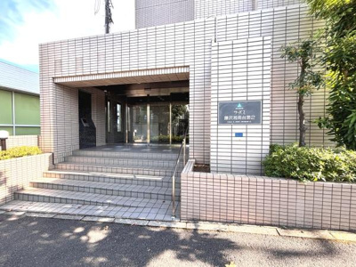 広い階段と手すり付きのエントランスが来訪者を迎え入れる印象です。タイル張りの外観が落ち着いた雰囲気を演出しています。植栽スペースがあり緑も感じられる空間となっています。