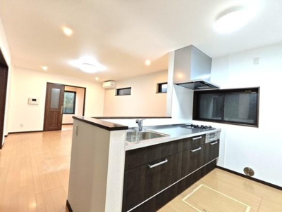 開放感のあるキッチンが魅力です。広めのカウンターと収納が特徴的です。ダークカラーの扉が落ち着いた印象を与えます。換気窓があり明るく快適な空間になっています。