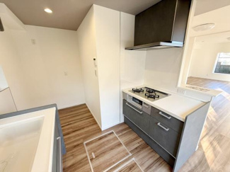 木目調のフロアが明るい空間を演出しています。シンプルで使いやすいキッチンレイアウトです。コンロやシンクもバランスよく配置されています。広々としたスペース設計です。清潔感のある内装が印象的です。