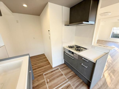 木目調のフロアが明るい空間を演出しています。シンプルで使いやすいキッチンレイアウトです。コンロやシンクもバランスよく配置されています。広々としたスペース設計です。清潔感のある内装が印象的です。