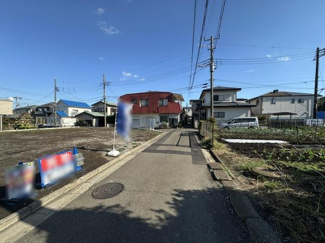 現地前面道路の幅員がしっかり確保されており車両の出入りもスムーズに行えます。周辺には住宅が建ち並び落ち着いた雰囲気の街並みです。電柱や配線も整然としており道路の整備状況も確認できます。
