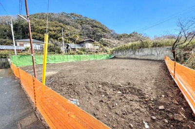 静かな環境に位置する外観写真です。周囲には自然が広がり広々とした土地の様子が魅力的です。視界を遮る高い建物がなく開放的な印象を受けます。オレンジのフェンスが敷地の範囲を明確にしています。