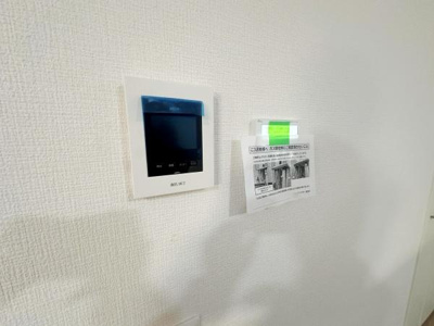 壁に設置されたモニター付きインターホンが備わっています。ホワイトのクロスと調和したシンプルなデザインです。来訪者を確認できる点が特徴です。見やすい位置に配置されています。