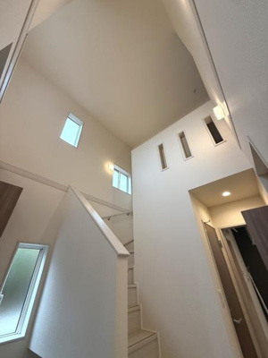 吹き抜けのある開放的な空間が広がります。壁のスリット窓がアクセントとなり明るさを演出しています。階段や廊下もすっきりとしたデザインです。採光にも工夫が感じられます。シンプルで整った印象です。