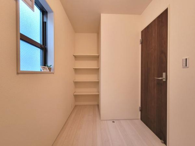壁面の収納棚が設置されており整理しやすい空間です。シンプルな内装で使い勝手の良い収納スペースとなっています。窓もあり明るい雰囲気が感じられます。出入口も広くアクセスしやすさも特徴です。