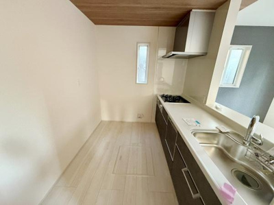 キッチンにはスリムな窓があり自然光が入る明るい空間です。収納が多く調理スペースも確保されています。コンロとシンクが一直線に配置され家事動線もシンプルです。カウンター越しにリビングを見渡せる設計です。