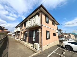 落ち着いたトーンの外観が印象的です。各住戸にはバルコニーが設けられています。建物前面には駐車スペースも確保されています。周辺には住宅が並び開放感も感じられます。空の広がりが感じられる建物です。