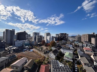 晴れた日の青空が広がり遠くまで見渡すことができる眺望です。周囲には高層マンションや住宅が立ち並び街並みを一望できます。開放的な空間が印象的で都市の風景を楽しめます。自然光がしっかり入る明るい環境です。
