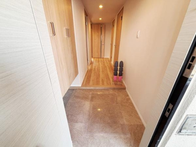 玄関はゆとりのあるスペースが確保されており落ち着いた色合いの床材が印象的です。収納も充実しており靴などをすっきりと収めることができます。照明が明るく室内への入り口として清潔感があります。