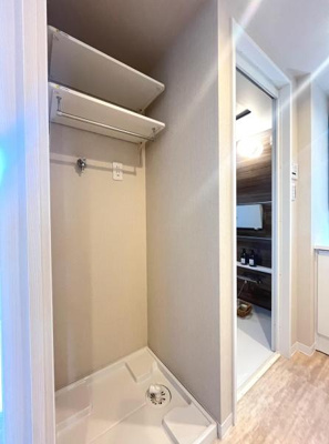 壁面に設置された棚が空間を有効活用しています。ハンガーパイプ付きで衣類の収納に便利です。奥行きのある形状が特徴的です。隣接するスペースへの動線もスムーズです。清潔感のある仕上がりです。