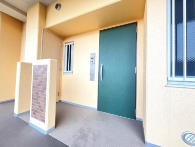 玄関は広々としており荷物の出し入れもスムーズに行えます。明るい色合いの外壁と落ち着いた色の扉が印象的です。オートロック付きで安心感も高まります。小窓があり採光にも配慮されています。