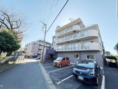 明るく開放感のある外観が目を引くマンションです。敷地内には駐車スペースがしっかり確保されています。周囲には緑も感じられる住環境です。道幅も広く車の出し入れがしやすい配置です。