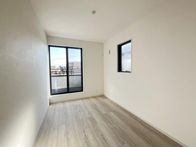 大きな窓から光が差し込む明るい洋室です。シンプルな内装でどんな家具にも合わせやすい空間となっています。木目調の床が温かみを感じさせるお部屋です。清潔感のある白い壁も特徴的です。