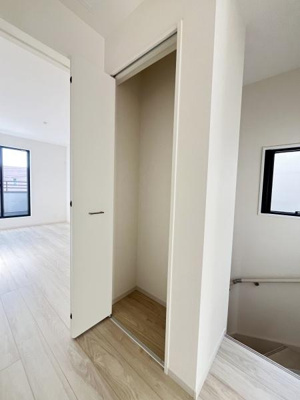 シンプルなデザインの収納スペースが設置されています。扉付きで空間を活かしたすっきりとした印象です。廊下の一角に位置しており使いやすさも感じられます。階段横の配置で動線も考慮されています。