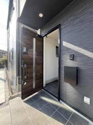 シンプルなデザインの玄関ドアが印象的です。モダンな外観と調和したタイルが統一感を演出しています。玄関まわりが広く使いやすい印象です。宅配ボックスなどの設備も備えられています。