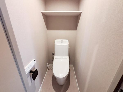 シンプルなデザインのトイレでお手入れがしやすい造りです。壁面の収納棚があり備品の整理が可能です。空間がすっきりとしており清潔感があります。操作パネル付きで使い勝手も考慮されています。