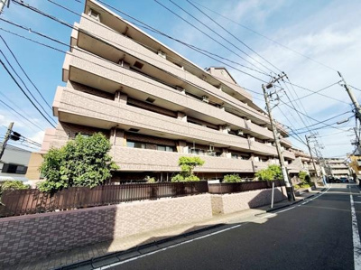 落ち着いた色合いの外観が印象的なマンションです。角地に位置しており開放感があります。道路に面した立地でアクセスの良さも感じられます。周囲には植栽が施され清潔感があります。