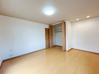 明るい色合いのフローリングが印象的な洋室です。収納スペースがしっかり確保されています。天井照明とダウンライトが室内を照らしています。すっきりとした空間が広がっています。
