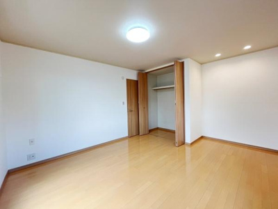 明るい色合いのフローリングが印象的な洋室です。収納スペースがしっかり確保されています。天井照明とダウンライトが室内を照らしています。すっきりとした空間が広がっています。