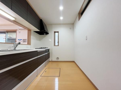 シンプルでスッキリとしたキッチン空間です。作業スペースも広く使い勝手に配慮されています。窓があり換気がしやすい設計です。収納もしっかり備わっています。天井のダウンライトで明るさが確保されています。