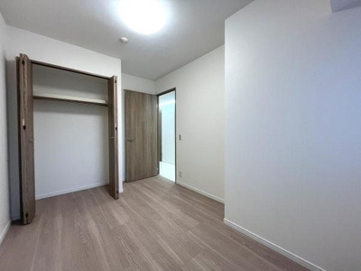 シンプルで落ち着いた雰囲気の洋室です。クローゼット付きで収納スペースも確保されています。ナチュラルなフローリングが特徴的です。壁や天井もホワイト基調で明るい印象があります。