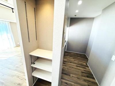 ナチュラルな木目調のフローリングが特徴的な空間です。使いやすい可動棚が設置されています。廊下部分もすっきりとしたデザインで室内全体に明るさがあります。開放的な窓から光が差し込む印象を受けます。