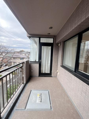 幅広いバルコニースペースがゆとりを感じさせます。透明な手すり部分から外の景色も楽しめます。床や壁のタイル調デザインが落ち着いた印象を与えます。窓からの光も十分に入り明るい空間です。