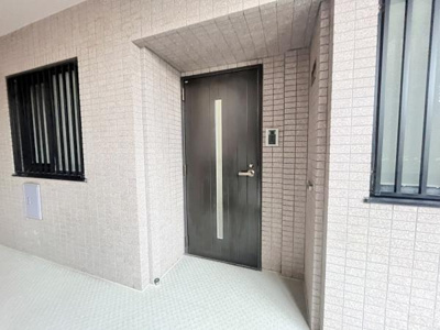 すっきりとしたデザインの玄関ドアが印象的です。モダンな外観で清潔感があります。屋根付きのアプローチが天候から玄関を守ります。両側に窓が配置されており明るい印象です。インターホンも設置されています。