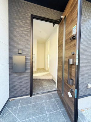 シックな色合いの玄関が落ち着いた雰囲気を演出します。ゆとりのあるスペースで出入りがしやすい設計です。玄関ドアのデザインが外観にアクセントを加えています。タイル張りの床が清潔感を感じさせます。